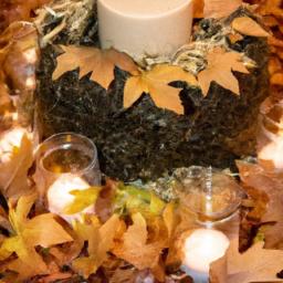 Create a cozy atmosphere for your fall dinner party with this hay bale centerpiece featuring candles and autumnal foliage.