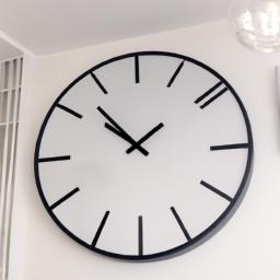 This large black metal frame wall clock with a white face adds a sleek and modern touch to the living room decor